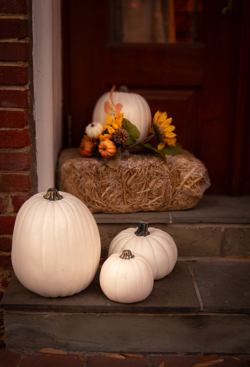 Fall porch with white pumpkins, hay and autumn flowers