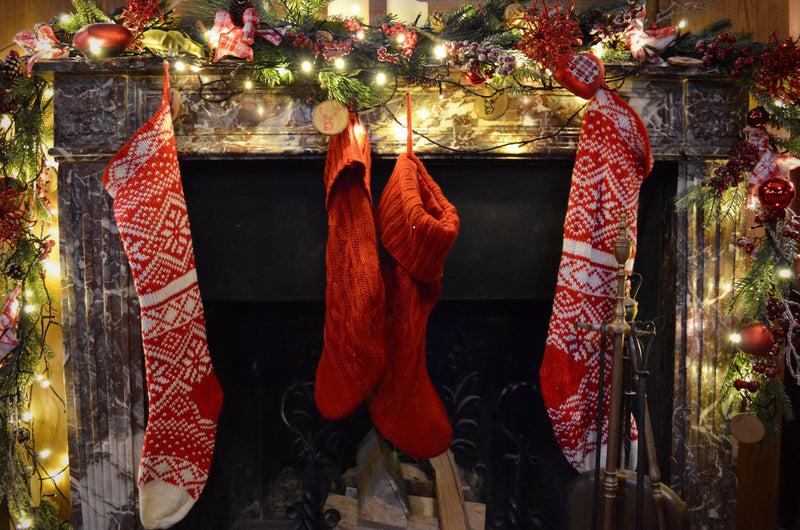 Christmas stockings hanging on a lit fireplace mantel