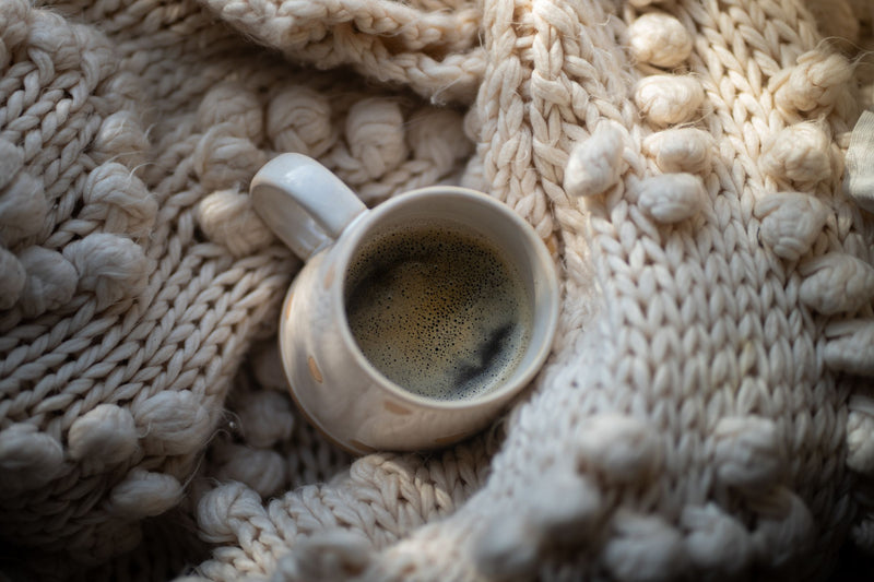 Coffee mug nestled in a chunky knit blanket