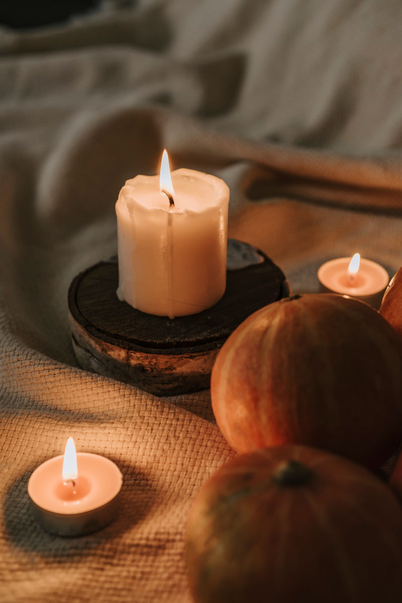 Lit candles and pumpkins in warm autumn candlelight